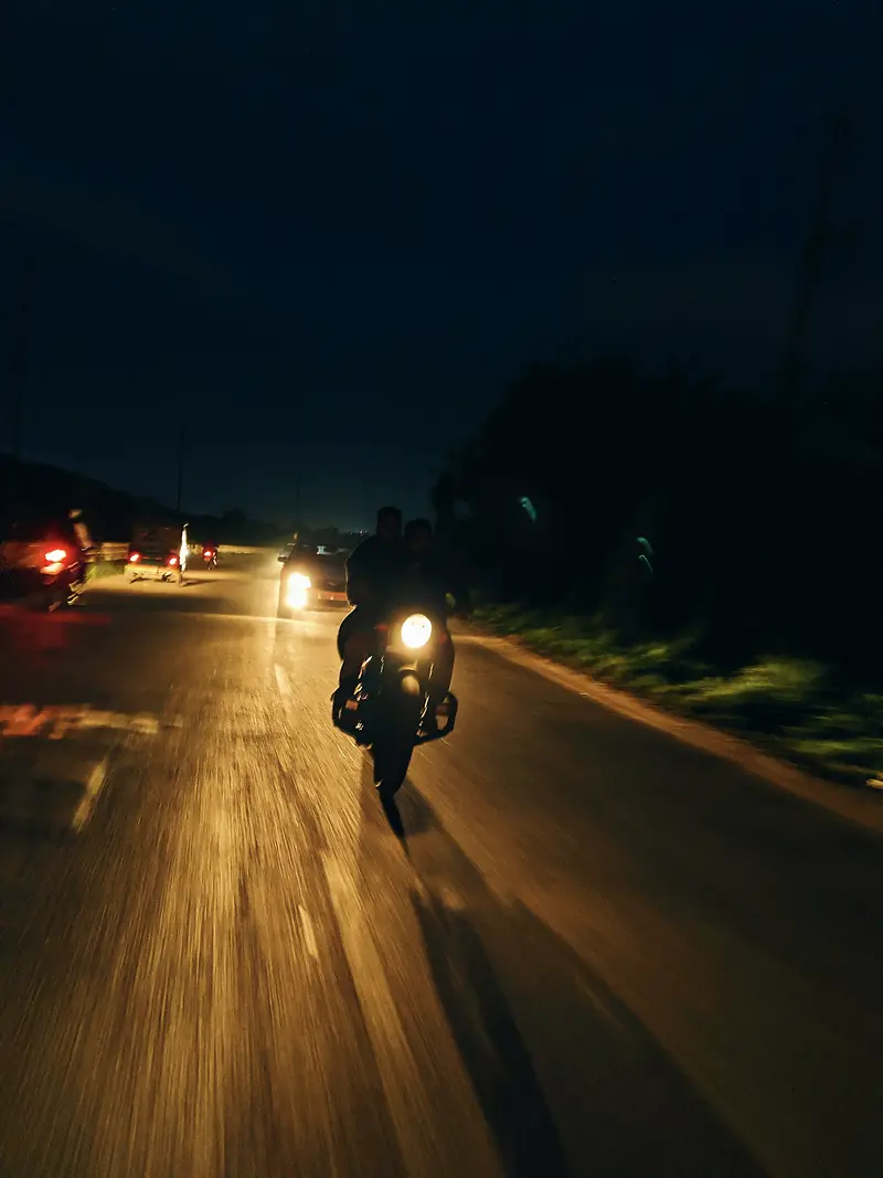 Moto roulant de nuit sur une route éclairée par son phare