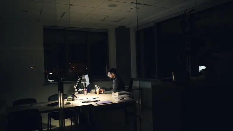 Bureau de nuit, un enquêteur travaille à son ordinateur sous une lampe